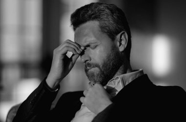 Yorgun adamın korkunç bir baş ağrısı var. Bitkin, sağlıksız hisseden, baş ağrısı hastalığına üzülen bir adam. Stresli orta yaşlı bir adamın baş ağrısı olan portresi. Migren ve baş ağrısı konsepti