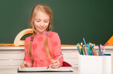 School concept. Kid writing on textbook. Little student doing homework at elementary school. Little girl pupil study in classroom