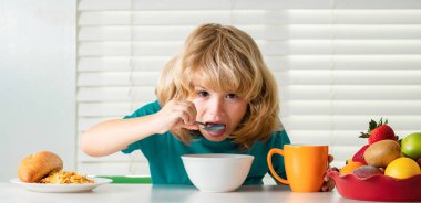 Hunger, appetite concept. Funny blonde little boy having breakfast. Milk, vegetables and fruits healthy food nutrition for children