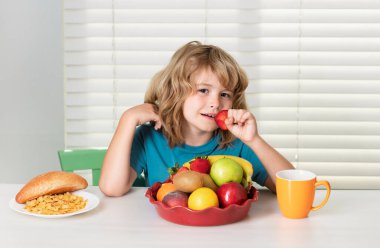 Çocuk çilek yiyor, organik meyveler. Vitaminli sağlıklı sebzeler. Gerçek çocuk beslenme konsepti