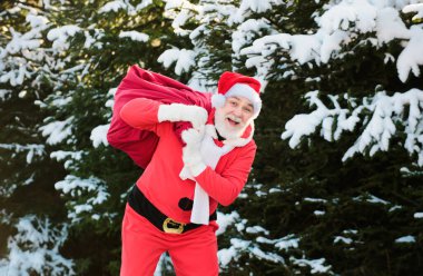 Noel Baba bir çanta dolusu hediyeyle kış dağlarında yürür.