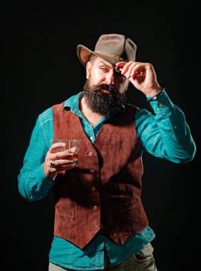 Sakallı adam elinde bardak brendi tutuyor. Siyah takım elbiseli, kendine güvenen sakallı bir adam ve çatı katında bir bardak viski. Alkol iç.