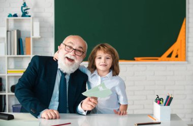 Mutlu büyükbaba ve torun kucaklaşması portresi, okuldaki öğrenci öğretmeni kucaklıyor. İlkokulda eğitim, çocukların öğrenme konsepti