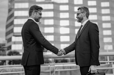 Selamlama, satış, birleşme ve satın alma konsepti. İki iş adamı arasında tokalaşma. Şehir caddesinde el sıkışan iki işadamı. Takım elbiseli işadamları dışarıda el sıkışıyor. İş ekibi