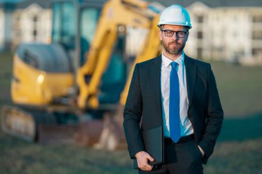 İnşaat alanında mimar. İnşaat alanında kask ve takım elbiseli mimar. İnşaatta duran kendine güvenen bir mimar. Yatırımcı ya da inşaat mühendisi. İspanyol 'un açık hava portresi