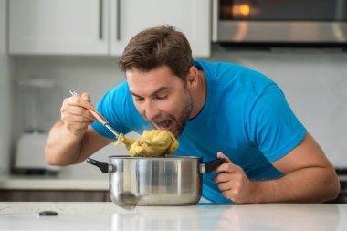 Aşçı adam mutfakta tencerede yemek pişiriyor. Gurme yemeği hazırlama süreci. Adam evde yemek pişiriyor, esrar kullanıyor. Şef yemek pişiriyor. Yakışıklı aşçı aşçı konsepti