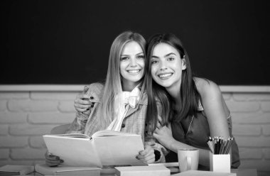 Mutlu gülümseyen öğrenciler kolejdeki sınıfta sarılıp kucaklaşıyorlar.