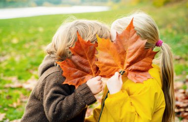 Parkta oynayan güz yapraklı mutlu çocuklar
