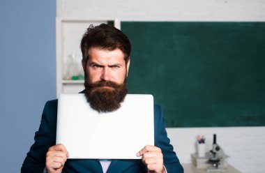 Ciddi bir öğretmen dizüstü bilgisayar tutuyor, öğretmen sakallı profesör duygularını ifade edemiyor.