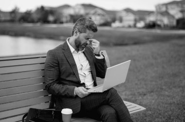 Takım elbiseli yorgun iş adamının bankta oturmasından sıkıldım. Yorgun yönetim kurulu başkanı dizüstü bilgisayarda çalışıyor. Yorgun iş adamları streslidir. Baş ağrısı migreni. Parkta dizüstü bilgisayardan çalışan yorgun serbest çalışan bir adam.