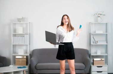 Dizüstü bilgisayarı ve kredi kartı olan genç bir iş kadını. Mali planlama