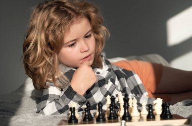Küçük çocuk evde satranç oynuyor. Akıllı konsantre ve düşünen bir çocuk satranç oynuyor. Çocuk satranç stratejisi geliştiriyor, masa oyunu oynuyor