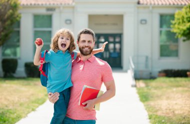 Baba oğul okul parkında yürüyorlar. Ailesi birinci sınıfta küçük bir çocuğu yönetiyor.