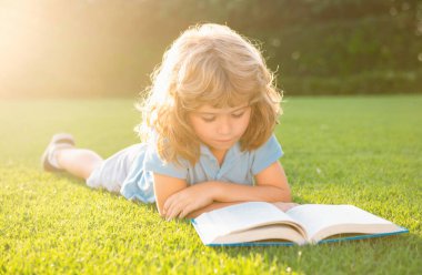 Zeki zeki çocuklar. Çim arka planıyla ilgili güzel bir çocuk kitabı. Çocuklar parkta kitap okuyor.