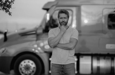 Kamyonun yanında erkek sürücü var. Kamyonetin yanındaki tişörtlü adam. Yakışıklı, orta yaşlı kamyoncu kamyoncu adam. Yarı karavan, yarı kamyon. Kamyonun önünde poz veren yakışıklı bir adam.