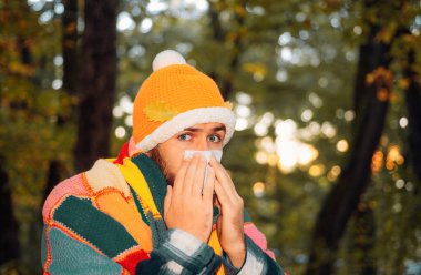 Sağlık ve tıp kavramı - sonbahar park kağıt dokusu ile hasta adam. Olgun adam soğuktan acı ceketli. Grip sezonunda, aşı. Grip epidemy durdurmak