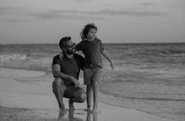 Gündüz vakti baba oğul kumsalda kucaklaşıyorlar. Arkadaş canlısı bir aile. Babalar Günü. Aşk ailesi, baba ve oğlu sahilde deniz doğasında birlikte yürürler. Ebeveynlik, babalık, babaların sevgisi.