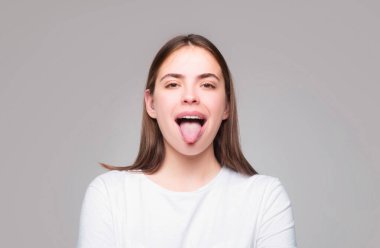 Beautiful modern model shows tongue. Model with sticking tongue out. Girl showing tongue. Emotional mouth with licking lips. People emotions lifestyle