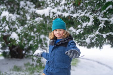 Kartopu eğlencesi. Çocuk kartopu oynuyor. Noel tatili, kış aile tatili. Çocuk Kartopu savaşının tadını çıkarıyor. Kışlık elbiseli çocuk kartopu atıyor. Kışın çocuklar, karla oynayın, kartopu yapın.