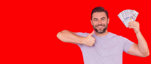 Хорошая оплата. Красавчик, держащий деньги в изоляции над красной студией, пространство для баннеров. Деньги в банкнотах. Куча наличных, финансов, инвестиций и сбережений. Мокап-баннер