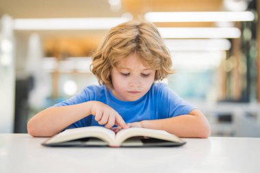 Çocuk kitabı okuyor. Halk kütüphanesinde kitap okuyan bir çocuk. Okul kütüphanesinde kitap okuyan bir çocuk. Okumak için edebiyat seçen zeki bir kız. Kitapçıdaki raflardaki kitaplar. Kitaplardan öğrenme