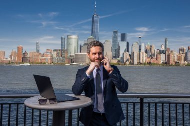 Başarılı ABD 'li işadamı. New York 'ta dizüstü bilgisayar kullanan bir adam. İş başarısı. Amerikan iş rüyası. Manhattan yakınlarında takım elbiseli Amerikalı iş adamları. ABD 'de online iş