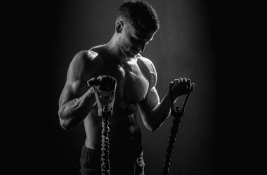 Sporcu adam süspansiyon antrenmanı yapıyor. Seksi kaslı adam uzaklaştırma eğitimi alıyor. Spor. Spor salonunda spor aletleri ile antrenman yapan adamlar. Kaslarını çalıştıran adam kol askısı ya da süspansiyon kayışı takıyor.