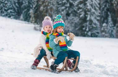 Kızaktaki çocuklar. Çocuklar, dışarıda karda oynuyorlar. Kış, tatil ve Noel zamanı. Yeni yıl duvar kağıdı, Noel tebrik kartı.
