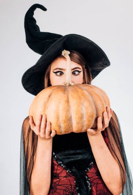 Komik surat ifadesi. Deli insanlar. Kadın kabak ile poz. Güzel genç kadın cadı şapka ve kabak tutan kostüm şaşırttı