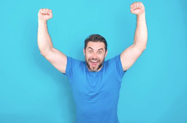 Heyecanlı adamın duygusallığı. İnsan tepkisi ve duyguları. Yüz ifadesi olan heyecanlı adama yaklaş. Mutlu ve heyecanlı adam, kazanan jest yapıyor. Kolları havada, gülümsüyor ve başarı için bağırıyor.