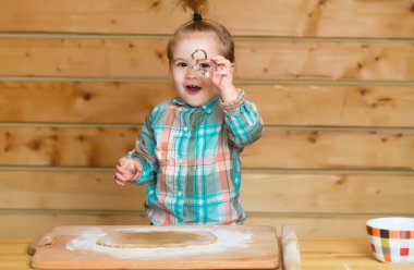 Mutfaktaki küçük aşçı çocuk. Gappy bebek kurabiye pişiriyor. Çocuk şirin bebek mutfakta ev yapımı fırın yapıyor. Çocuk masada oturuyor ve yemek yapmayı ya da pişirmeyi öğreniyor.