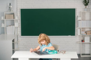 Okul çocuğu sınıfta dijital bilgisayar kullanıyor. İlkokul öğrenim programının komik öğrencisinin portresi