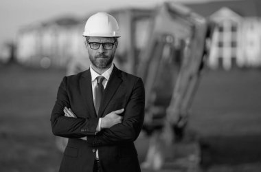 İnşaat işletmecisi ya da şantiye müdürü. İnşaat müdürünün portresi, kazıcının yanında şapka ve takım elbise giymiş. İnşaat yöneticisi veya denetçisi ile yenileme