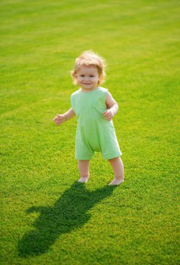 Parlak bir bahar gününde parkta yürüyen küçük bir çocuk.