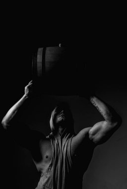 Güçlü adam, tahta fıçıyı siyaha tutar. Oktoberfest. Bira üreticisi. Kaslı adam. Bira fabrikası konsepti. Bar ve bar için bira. Meşe fıçıları, fıçı. Adam tahta fıçı taşıyor. Viski fıçısı.