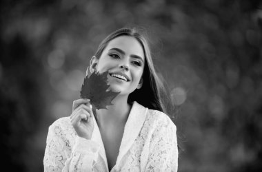 Sarı akçaağaç yaprağıyla sonbahar kadını, açık hava portresi. Sonbahar yapraklı güzel bir model, sonbahar parkında sarı akçaağaç. Sonbahar kızı sonbahar mevsiminde güneşli havanın tadını çıkarıyor.