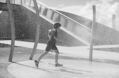 Sıcak yaz. Yazlık çocuk dışarıda su sıçratıyor. Çocuk, Miami Beach 'te yaz günü su sıçratmaktan hoşlanıyor. Çocuk açık hava çocuklarına su sıçratıyor umumi duş. Mutlu çocuk yaz çeşmelerinde oynuyor.