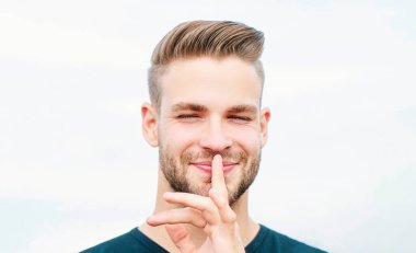 Dudaklarında parmak olan ciddi bir adam. Komplo mu? Ayrı yaşayan çekici adam sessizlik işareti gösteriyor.