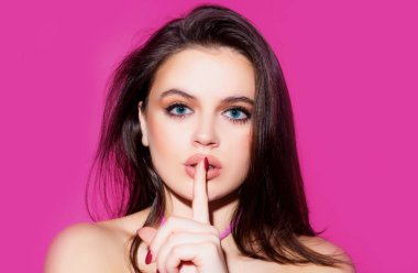 Kadın yüzü, dudaklarında parmak. Sessizlik hareketi. Şehvetli genç kadın modelinin portresi.