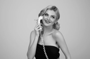 Sarışın kadın eski telefon hattından konuşuyor. Elinde antika telefon tutan kadın portresi. Telefon ahizeli kızı bağla. Eski model telefon ahizesi. Elinde telefon tüpü tutan bir kadın ilanı.