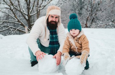 Mutlu Noeller ve mutlu yıllar. Kardan adam yapan mutlu baba ve oğul. El yapımı komik kardan adam. Baba ve çocuğun kar bahçesindeki kış portresi. Kış Baba ve Oğul