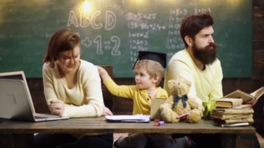 Baba ve anne sevgili oğluna resim çizmeyi ve resim yapmayı öğretiyor. Eğitim ailesi ve ev ödevi konsepti, mutlu baba ve oğul ev dersinde deftere yazıyor.