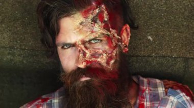 Cadılar Bayramı. Zombi adam. Cadılar Bayramı 'nda yüzünde kanlı yaralar olan ürkütücü bir adam. Yüzü kanlı zombi adam. Cadılar Bayramı için yaratıcı sanat makyajı. Adam korkunç zombiyle yüzleşiyor. Korkunç kâbus Cadılar Bayramı korku partisi
