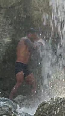 Erkek boksör dışarıda. İnsanlar doğadaki şelalede savaşırlar. Boksörler kavga eder. Boks sporu. Seksi bir adam. Tropik şelaledeki güçlü zinde adam. Vahşi doğa. Şelalenin altında boks yapan adam.