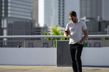 Şehirde telefonda konuşan yakışıklı bir adamın portresi. Modern büyük Amerikan şehrinde kendine güvenen bir adam telefonda konuşuyor. Şık bir Lambersex modeli. Polo giymiş seksi bir adam. Bisiness telefon görüşmesi