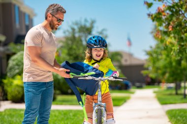 Babalar Günün kutlu olsun. Baba oğul bisiklete biniyor. Baba ve oğlu yaz parkında bisiklet sürüyor. Çocuk bisiklete binmeyi öğreniyor. Baba ve oğul kask takarak bisiklet sürüyor. Dışarıda bisiklete binen çocuk