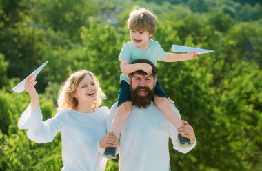 Çocuk babasının omuzlarında oturur. Baba, anne ve oğul birlikte oynuyorlar. Mutlu bir aile. Mutlu aile gülümsemesi ve kucaklaşması. Mutlu gülümseyen çocuk, baba kameraya bakıyor. Komik zaman.