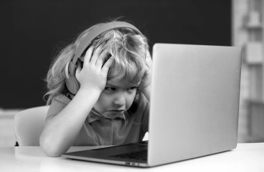 Öfkeli üzgün çocuk dizüstü bilgisayar kullanıyor, çocuk internette e-öğrenim görüyor. Küçük komik sistem yöneticisi