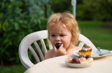 Bebek pasta yiyor. Çocukları beslemek. Çocuk yazın bahçede meyve yiyor.