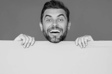 Tabela mutlu adamda, boş kart. Ürününüz için pankart hazır. Mesajını imzala. Gülümseyen adam stüdyo izole arka planında boş tabela gösteriyor. Boş tahta var. Reklam alanı